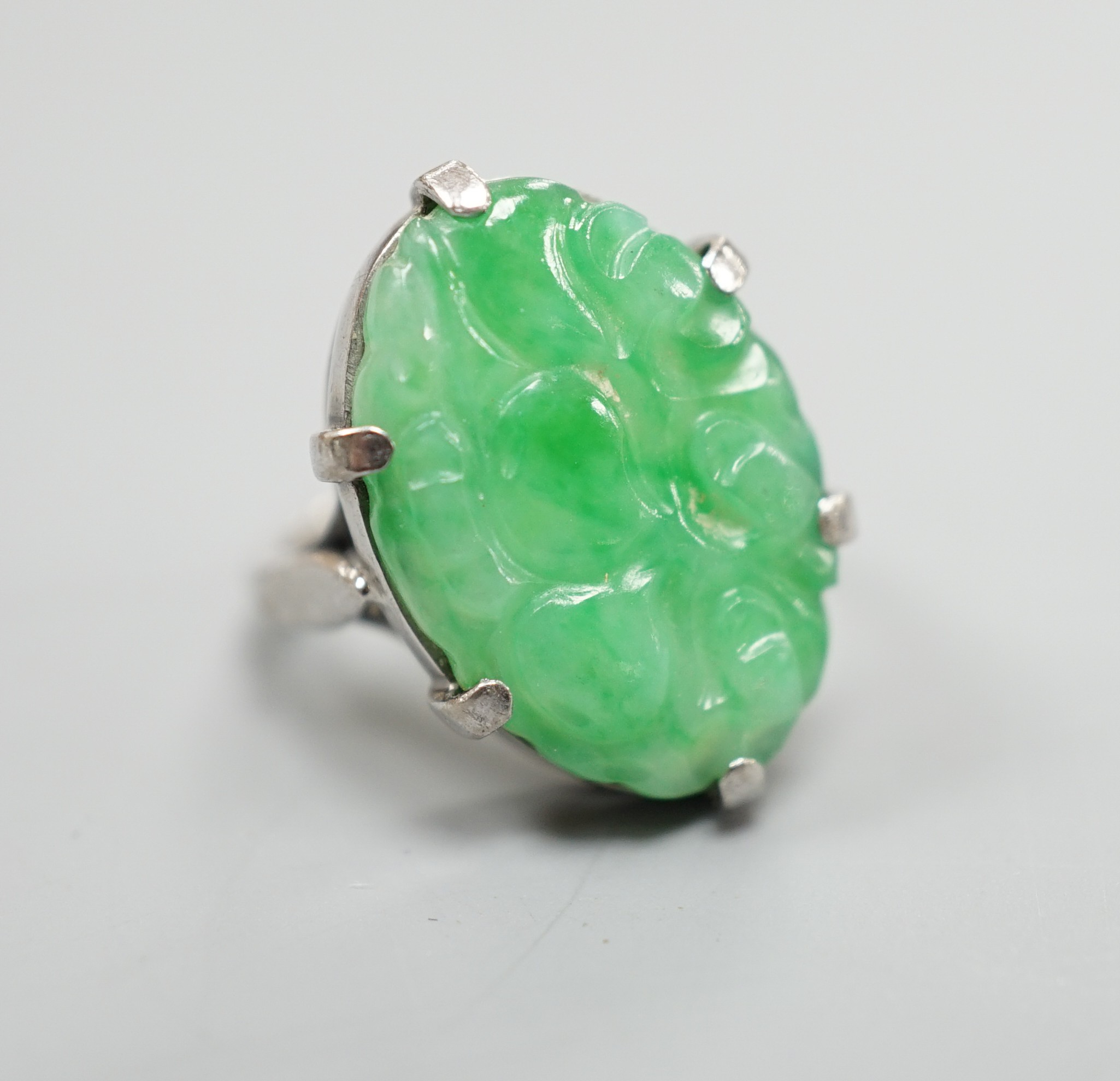 A white metal and oval jade set ring, carved with fruit, size F, gross weight 6.3 grams.